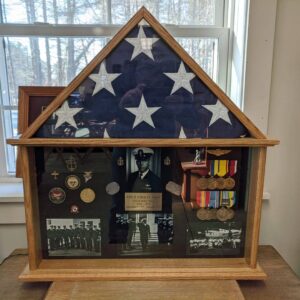 Import placeholder for 649 displays a folded American flag, medals, badges, and black-and-white photos in a wooden case.