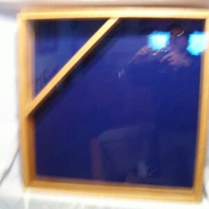 Import placeholder for 1050: Square wooden-framed glass panel with diagonal support, reflecting a blurry photographer.