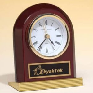 A small, wood-framed desk clock with Roman numerals and "Import placeholder for 1173" on the front plaque.