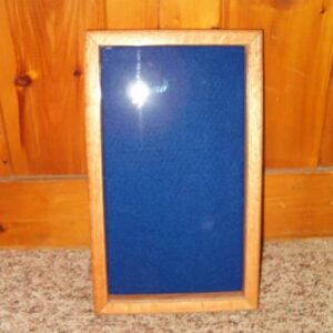 Import placeholder for 1339, a blue felt rectangular bulletin board with wooden frame, leans against a wood-paneled wall.