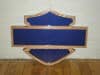 A blue, shield-shaped sign named "Import placeholder for 368" with a wooden frame, leaning on a white wall and floor.