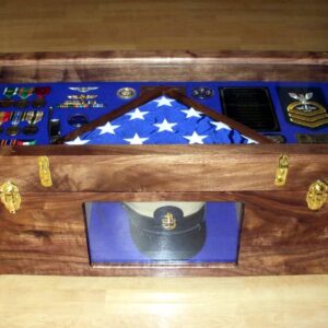 Import placeholder for 446: A wooden display case with a folded American flag, medals, plaques, and a uniform cap behind glass.