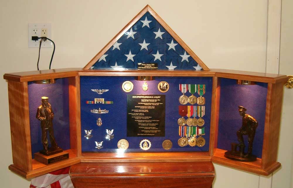 The Grand Colonial is a military shadow box with a folded flag, medals, ribbons, insignias, and two small statues.